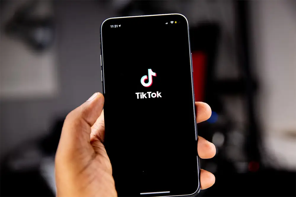 Mano sstienendo celular con el logo de Tiktok en la pantalla.