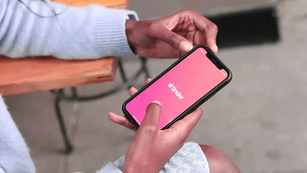 Persona usando Tinder en un smartphone, eligiendo fotos de perfil con la función"Selector de Fotos" basada en IA