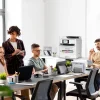 Impresora Epson WorkForce Pro EM-C800 en una oficina moderna con profesionales trabajando en equipo.