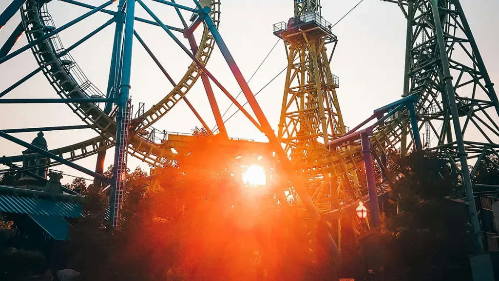 Montaña rusa en Six Flags con el sol brillando entre su estructura.