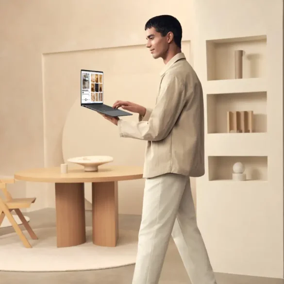Hombre usando una laptop ASUS Zenbook A14 mientras camina en un entorno moderno y minimalista, destacando su diseño ultraligero y portátil.