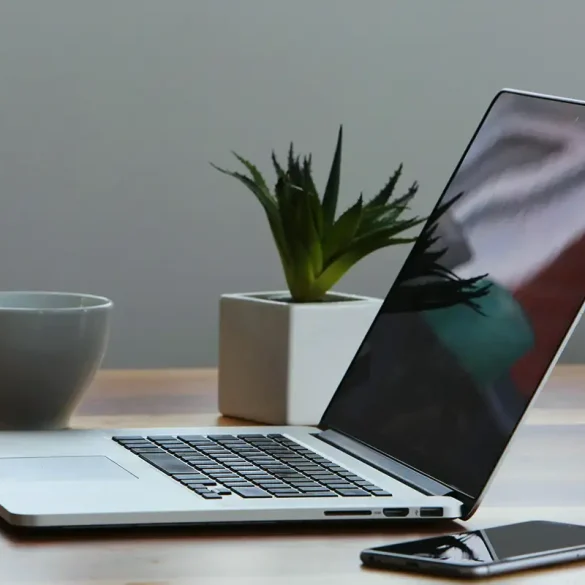 Escritorio con una laptop abierta, un smartphone, una taza de café y una planta decorativa, representando un entorno de trabajo digital minimalista, ideal para desarrolladores que utilizan soluciones en la nube como Cloudflare Workers VPC.