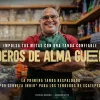 Tendero sonriente en su tienda con cartel de “Alma Guerrera” de Cerveza Indio al fondo