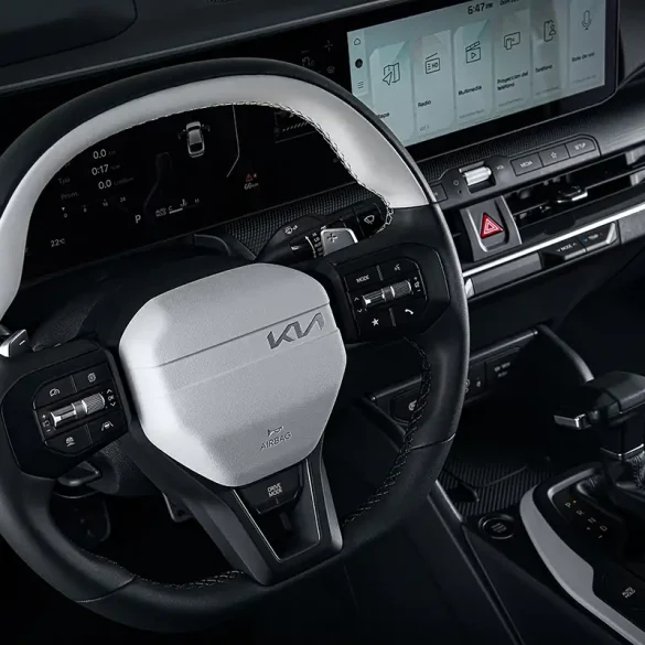 Volante del Kia K4 2025 con diseño bicolor, controles multifunción integrados y pantalla digital panorámica al fondo, destacando la experiencia de usuario intuitiva reconocida por Wards como una de las mejores del año.