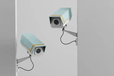 Dos cámaras de seguridad montadas en una pared vigilan en direcciones opuestas, simbolizando la vigilancia intramuros utilizada en negocios para prevenir robos sin violencia.