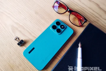 Smartphone HONOR X8c en color azul sobre escritorio de madera, acompañado de lentes, libreta negra, bolígrafo blanco y clip metálico.