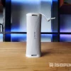 Bocina portátil Sony ULT Field 1 en color blanco, colocada en posición vertical sobre una mesa de madera, con fondo iluminado en tonos azules y morados, ideal para interiores modernos. Destaca su diseño compacto, textura de malla y correa ajustable.