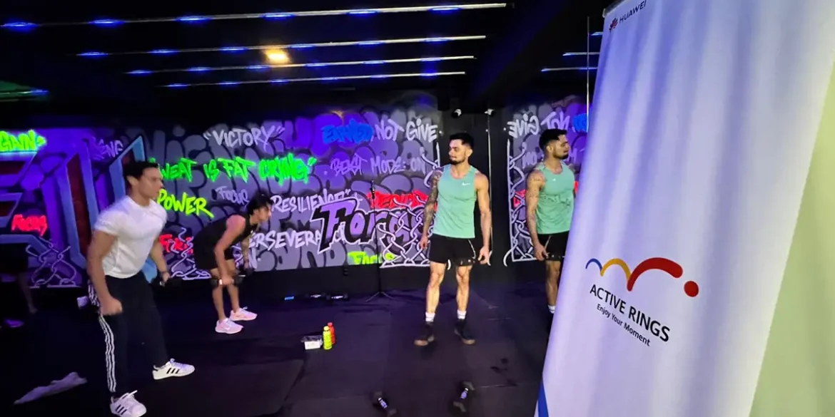 Entrenamiento funcional en Hell & Heaven Studio con el programa Active Rings de Huawei. Atletas realizan ejercicios de fuerza y resistencia en un entorno urbano con grafitis, mientras al fondo se observa un banner oficial del evento con el logo de la campaña.