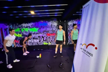 Entrenamiento funcional en Hell & Heaven Studio con el programa Active Rings de Huawei. Atletas realizan ejercicios de fuerza y resistencia en un entorno urbano con grafitis, mientras al fondo se observa un banner oficial del evento con el logo de la campaña.