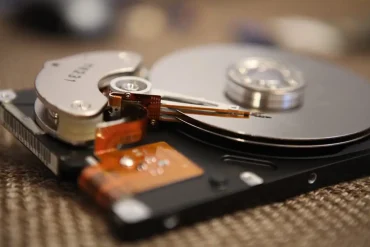 Primer plano del interior de un disco duro abierto, donde se observa el plato magnético y el brazo lector. La imagen ilustra la complejidad de los componentes internos de almacenamiento digital, clave en la investigación sobre falsificación detectada por Seagate.