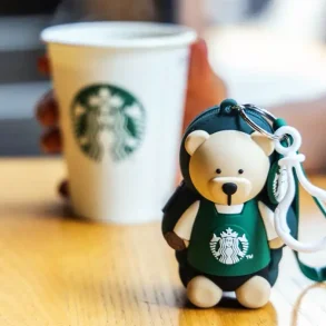 Llavero barista edición especial de Starbucks México 2025 junto a un café, símbolo de la campaña “Todos Sembramos Café”.