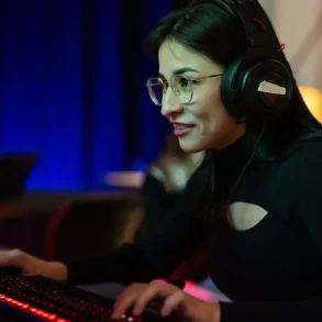 Estudiante concentrada juega en computadora con auriculares en un programa educativo basado en videojuegos.