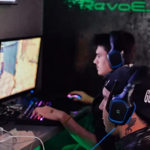 Dos jóvenes con audífonos profesionales juegan en computadoras de alto rendimiento, reflejando el auge del gaming competitivo y los esports en la era digital.