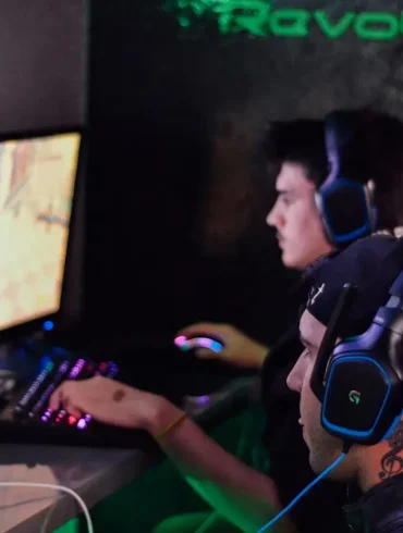 Dos jóvenes con audífonos profesionales juegan en computadoras de alto rendimiento, reflejando el auge del gaming competitivo y los esports en la era digital.