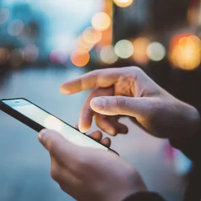 Persona usando un smartphone en la calle, ilustrando la conectividad móvil y la importancia de planes pospago flexibles con más gigas en México.