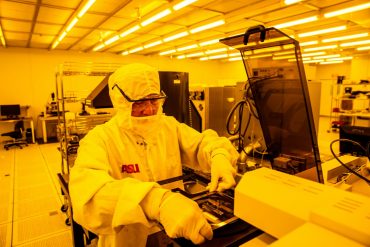 Arizona State University impulsa la formación de líderes en semiconductores en México Investigador de Arizona State University manipula obleas de silicio en un laboratorio de semiconductores equipado con iluminación amarilla controlada.