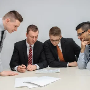 Cuatro profesionales analizan documentos financieros en una reunión de inversión, evaluando estrategias y perfiles de riesgo para optimizar resultados.
