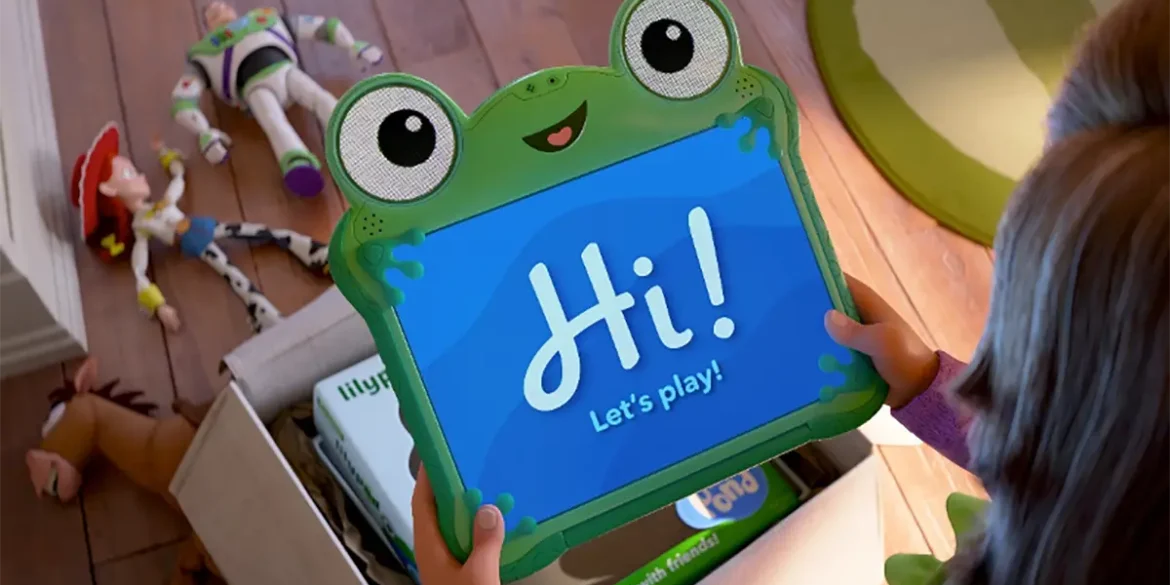 Niña sostiene tablet interactiva de rana con mensaje “Hi! Let’s play!” junto a juguetes de Toy Story en el suelo