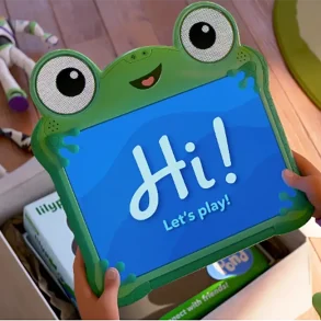 Niña sostiene tablet interactiva de rana con mensaje “Hi! Let’s play!” junto a juguetes de Toy Story en el suelo