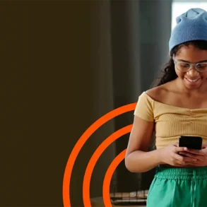 Mujer consulta su smartphone junto a un gráfico de señal Wi-Fi, imagen de Aprecomm sobre conectividad inteligente con IA